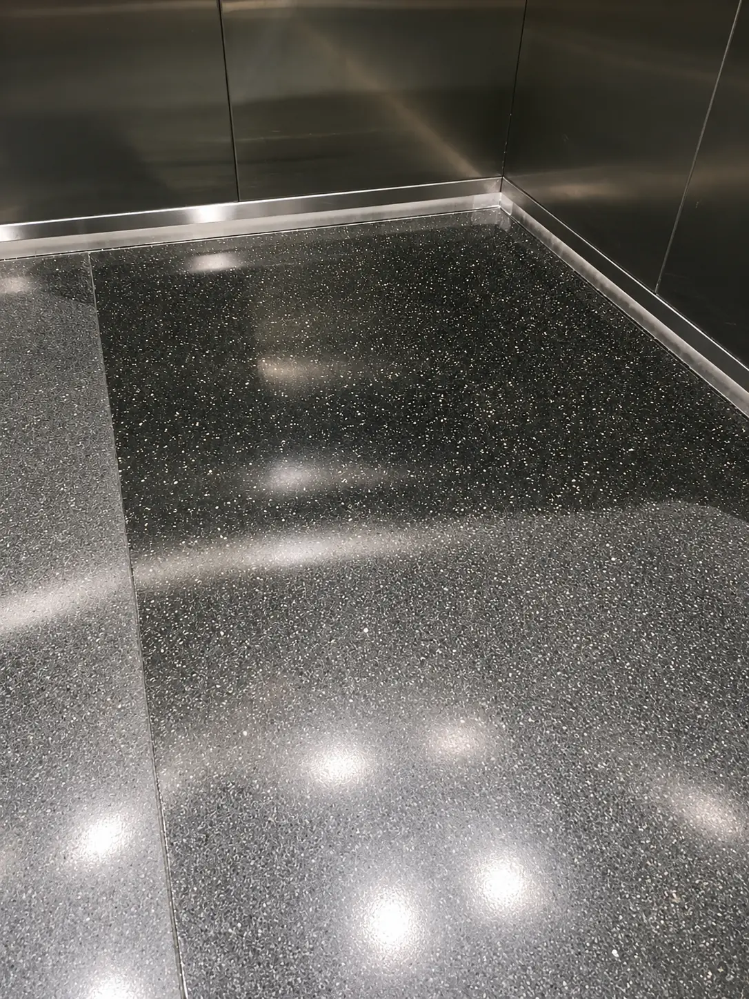 Black granite floor with a deep polished finish and clean light reflections