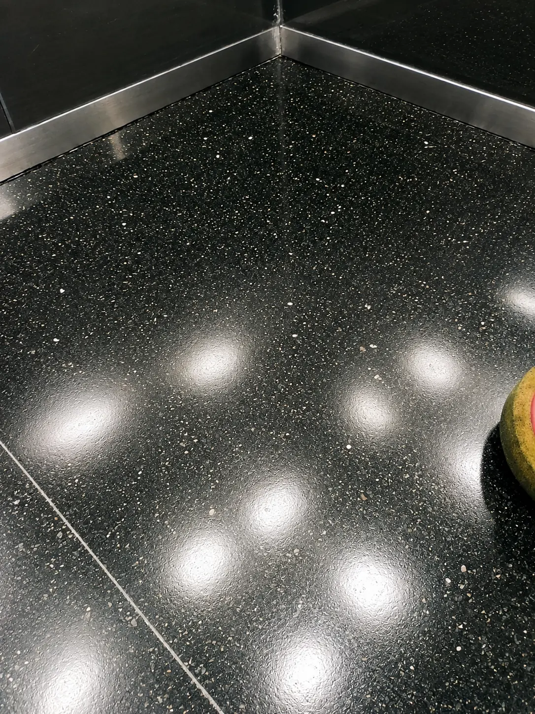 Close view of polished black granite reflecting ceiling spotlights