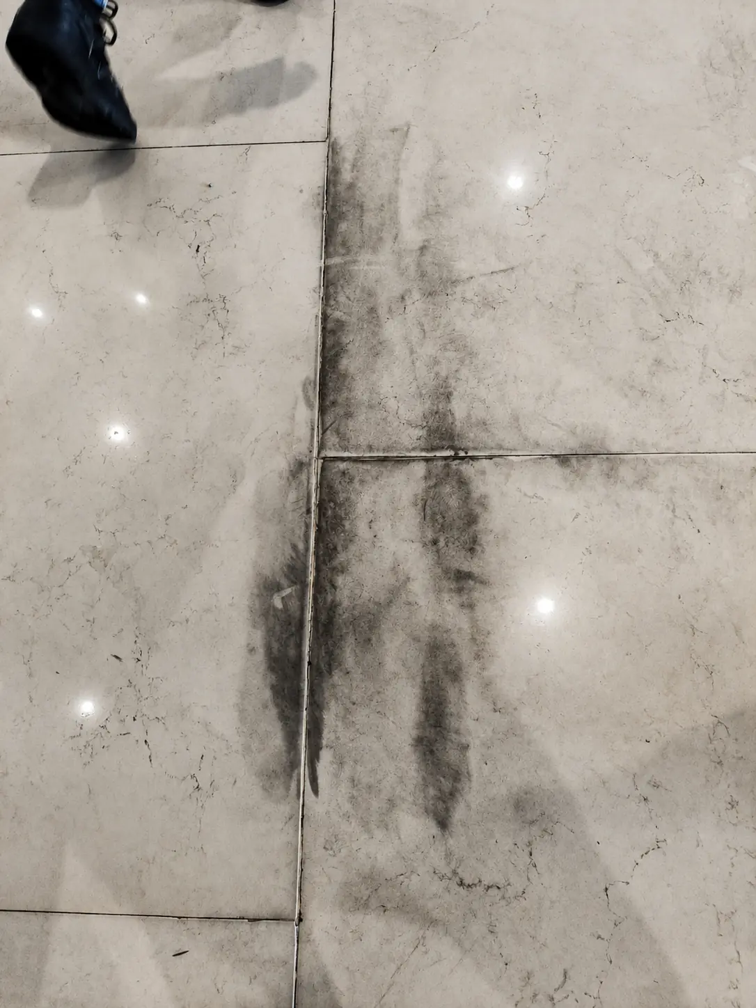 Marble floor showing dark traffic marks and embedded wear before treatment