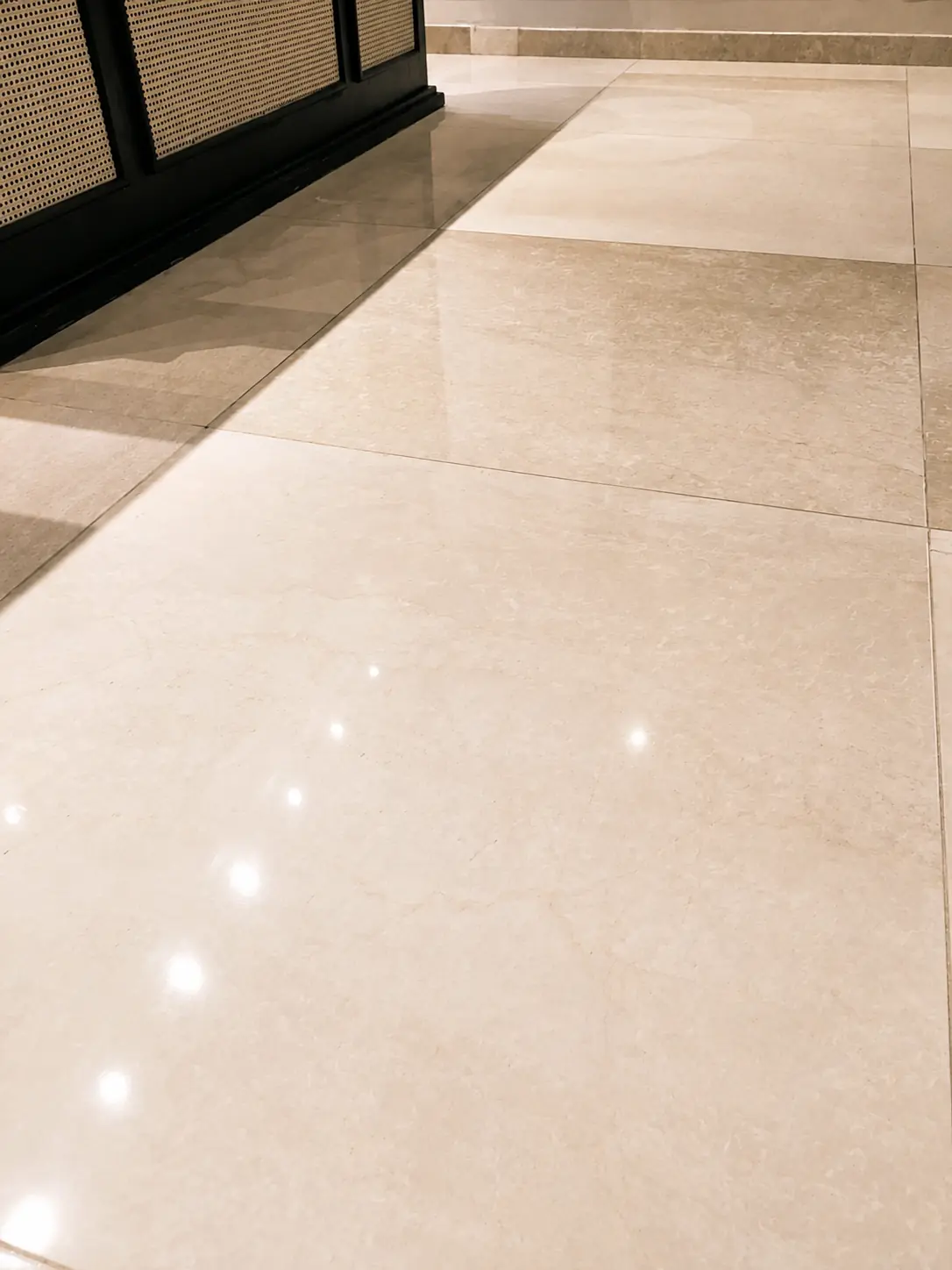 Beige marble floor with clean joints and an even reflective finish after professional surface care