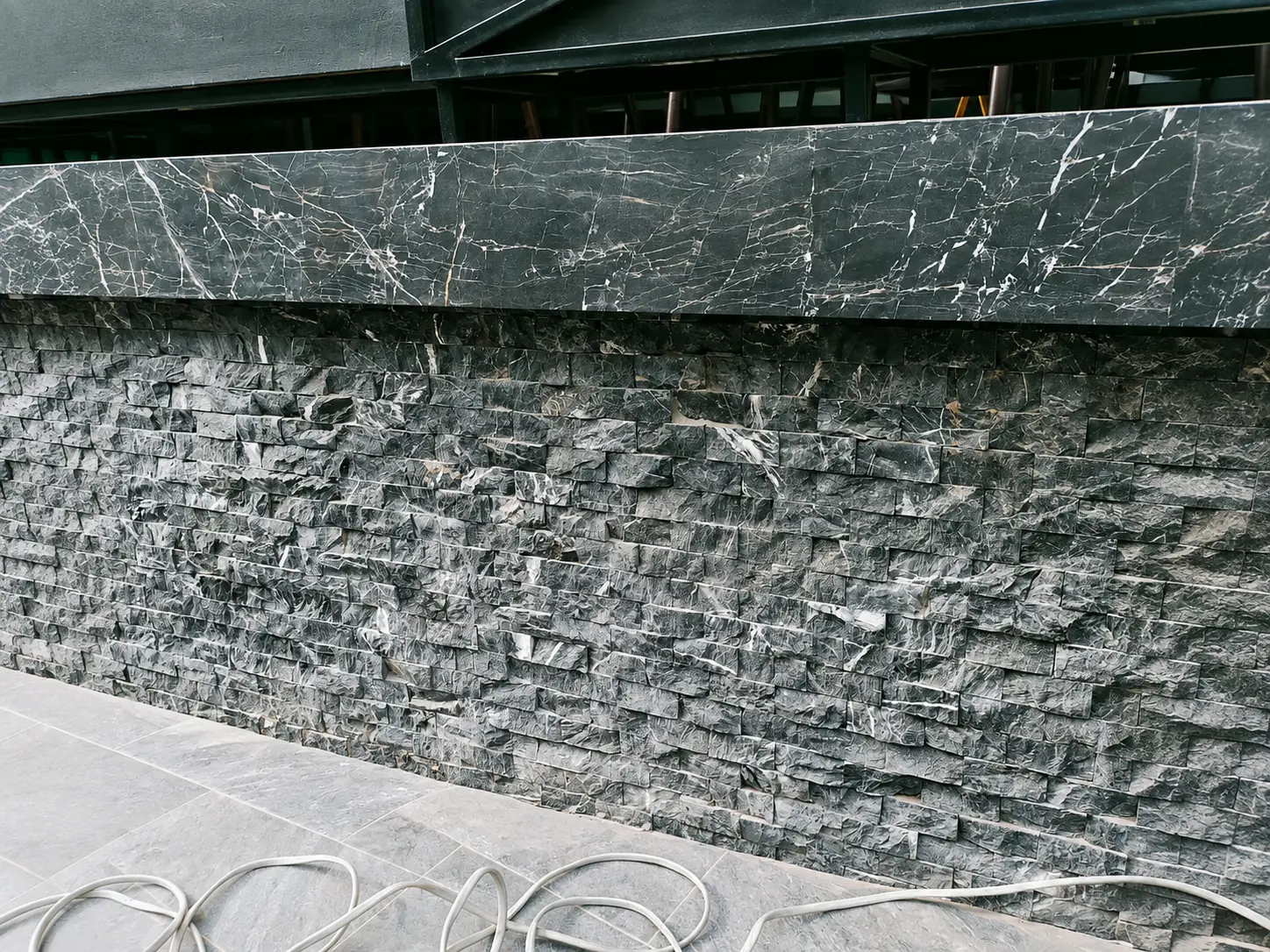 Dark natural stone pool wall documented before final handover